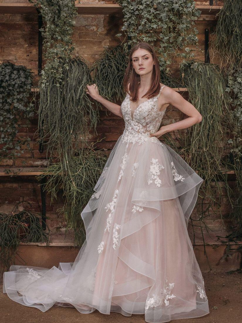 Braut im Brautkleid vor einer Mauer mit Pflanzen