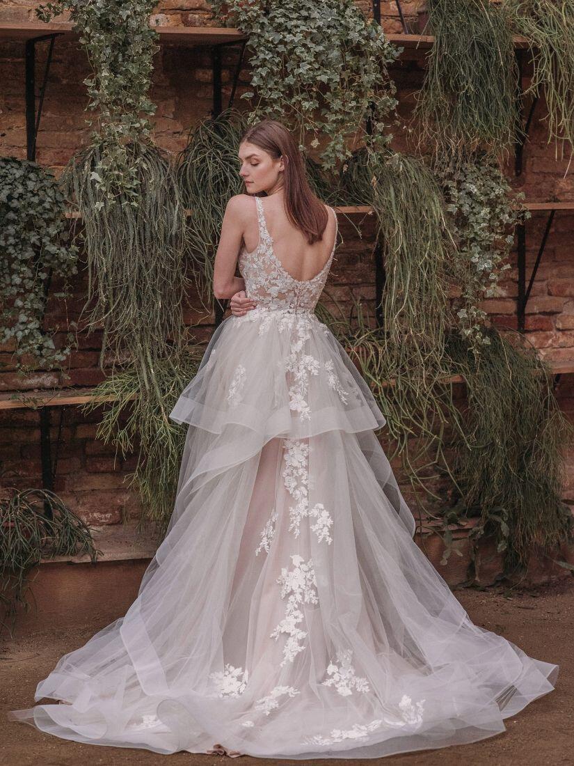 Braut im Brautkleid vor einer Mauer mit Pflanzen